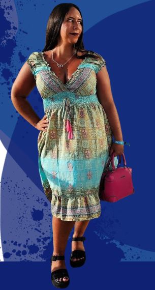 Sarah schaut zur Seite in einem bund gemusterten Kleid mit einer rosa Tasche.